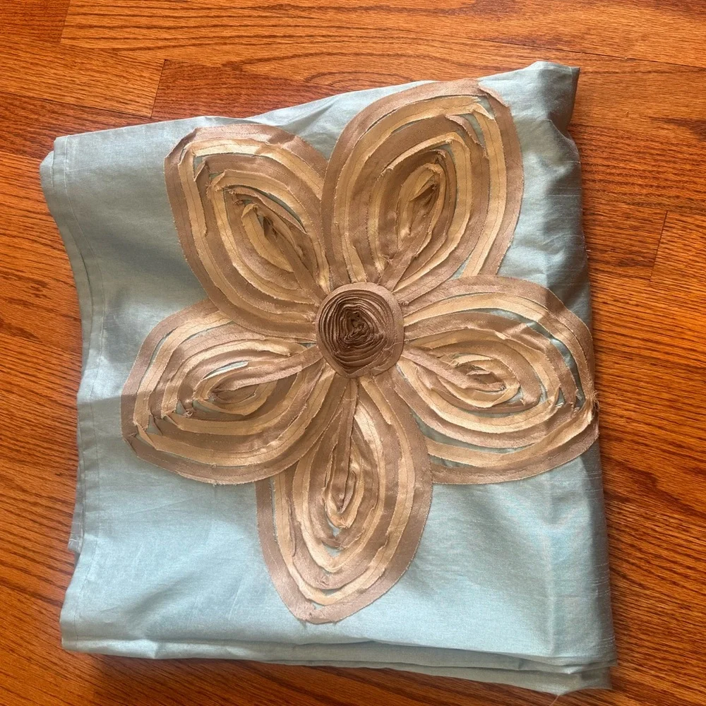 Fabric shower curtain in light teal with tan/gold flowers.
